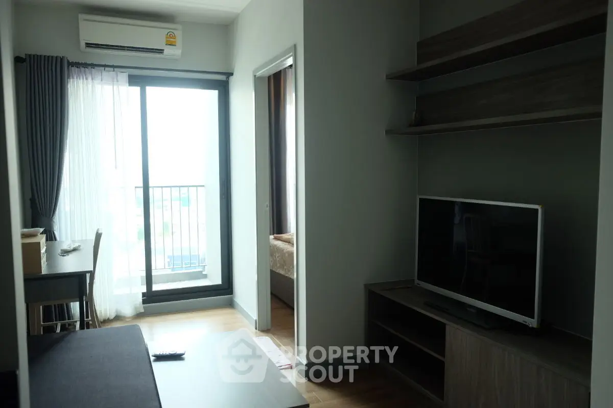 Modern apartment living room with balcony and TV unit, featuring sleek design and natural light.