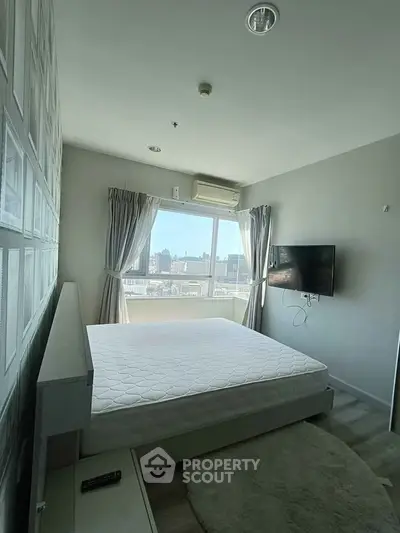 Modern bedroom with city view, featuring wall-mounted TV and air conditioning.