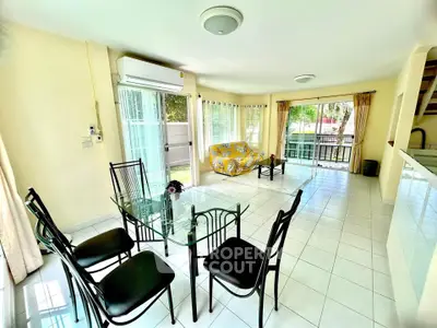 Spacious living room with glass dining table and garden view, perfect for family gatherings.