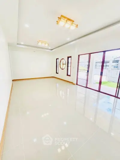 Spacious and bright living room with large windows and modern lighting fixtures.