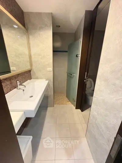 Modern bathroom with sleek design, featuring a spacious sink and glass shower enclosure.
