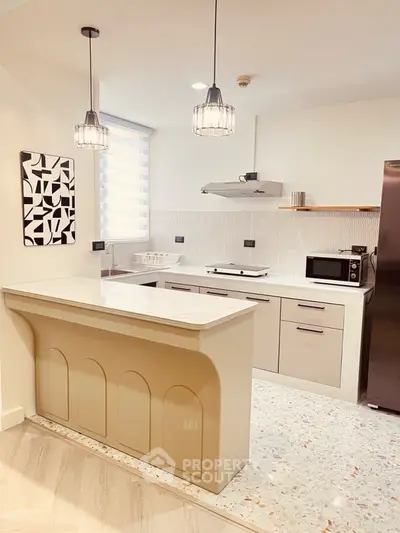 Modern kitchen with sleek design and open layout, featuring stylish lighting and contemporary appliances.