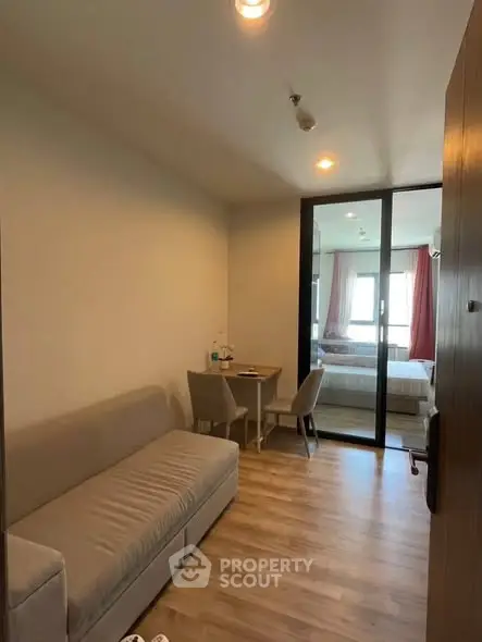 Cozy studio apartment with modern furnishings and wooden flooring, featuring a compact living area and bedroom.