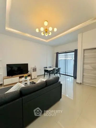 Modern living room with sleek furniture and elegant lighting, featuring a spacious open layout and large windows.