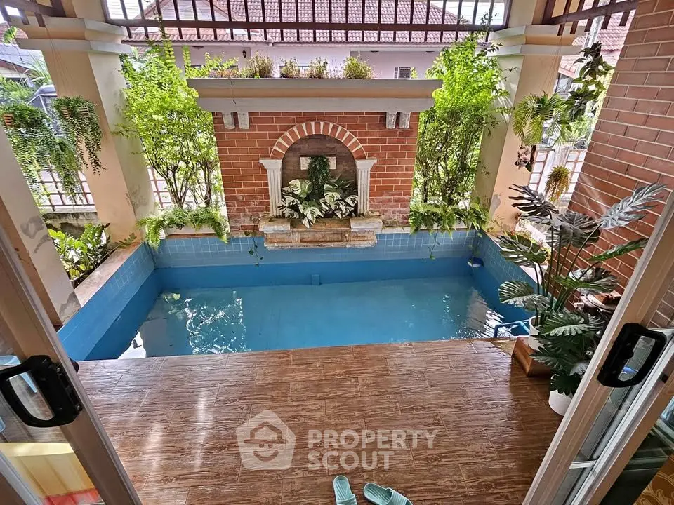 Charming indoor pool area with lush greenery and brick accents, perfect for relaxation and leisure.