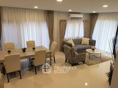 Elegant living room with modern furniture and dining area, featuring large windows and stylish decor.