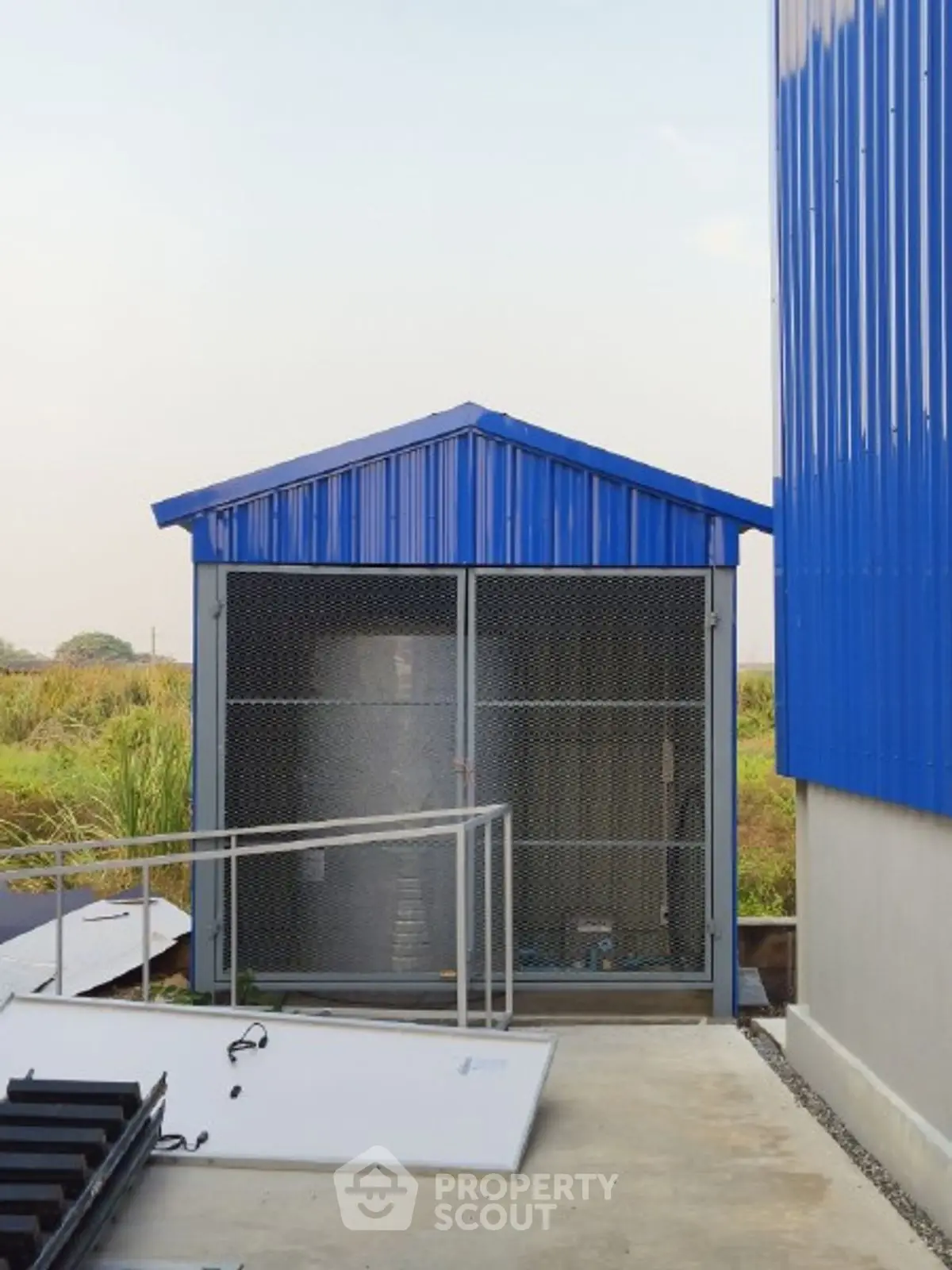 Modern industrial storage unit with blue metal roof and secure fencing.