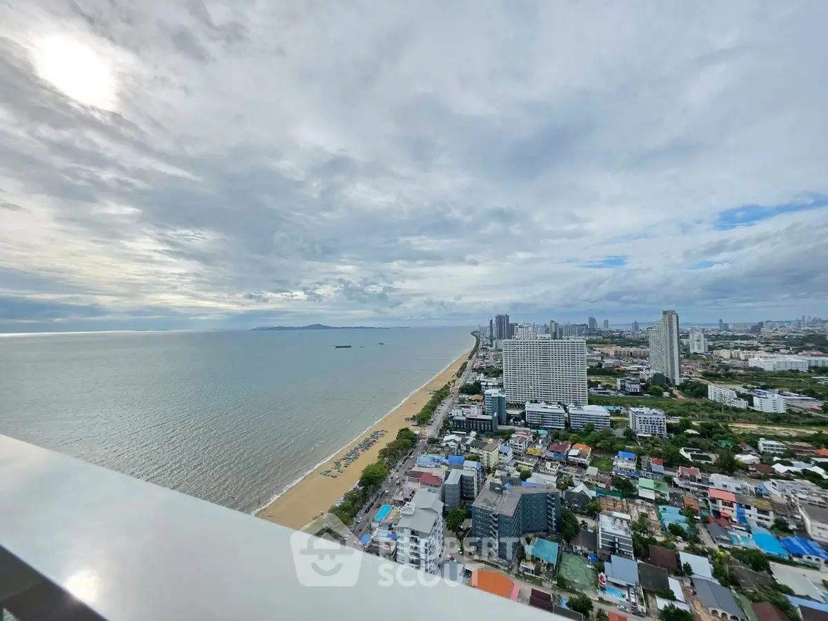 Stunning coastal city view from high-rise balcony overlooking ocean and skyline.