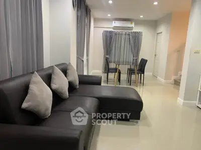 Modern living room with sleek black sofa and dining area in open layout