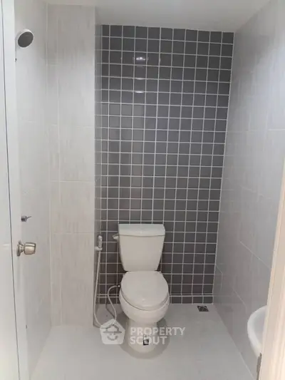 Modern bathroom with sleek gray tile accent wall and white fixtures.