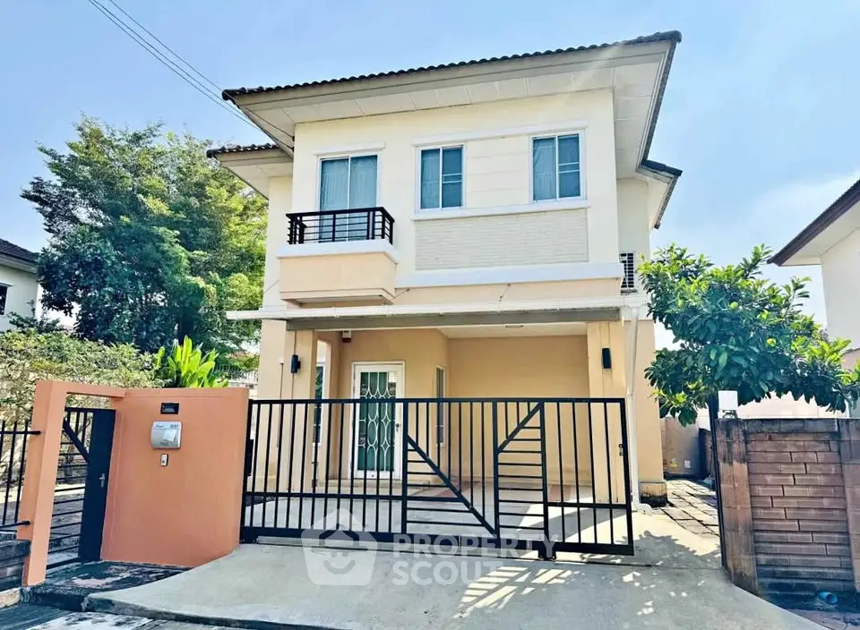 Charming two-story house with gated entrance and lush greenery in a serene neighborhood.