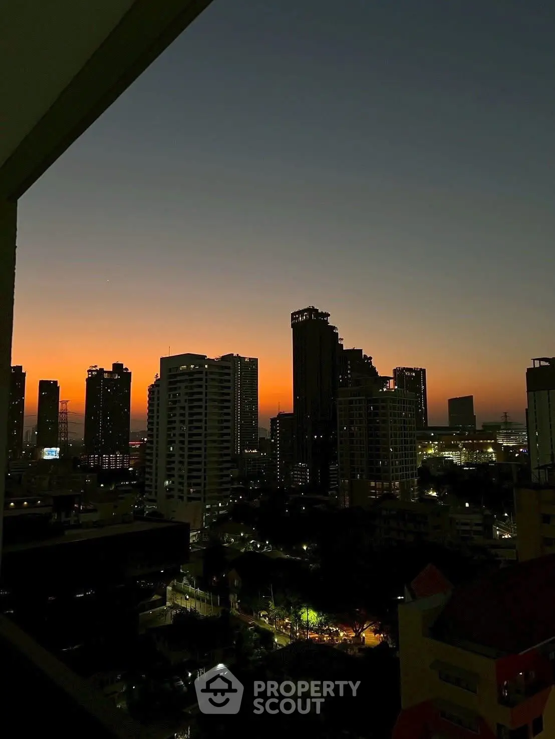 Stunning cityscape view from a high-rise balcony at sunset, showcasing urban skyline and vibrant evening lights.