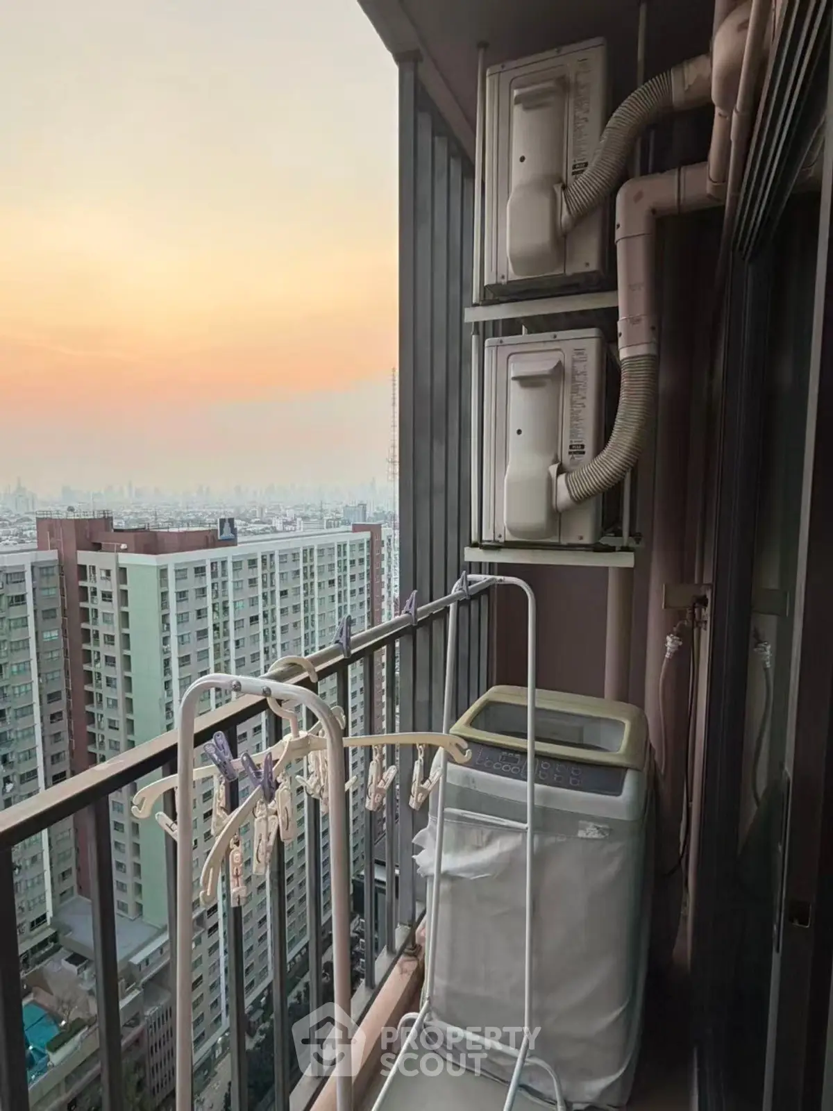 High-rise balcony with washing machine and city view at sunset