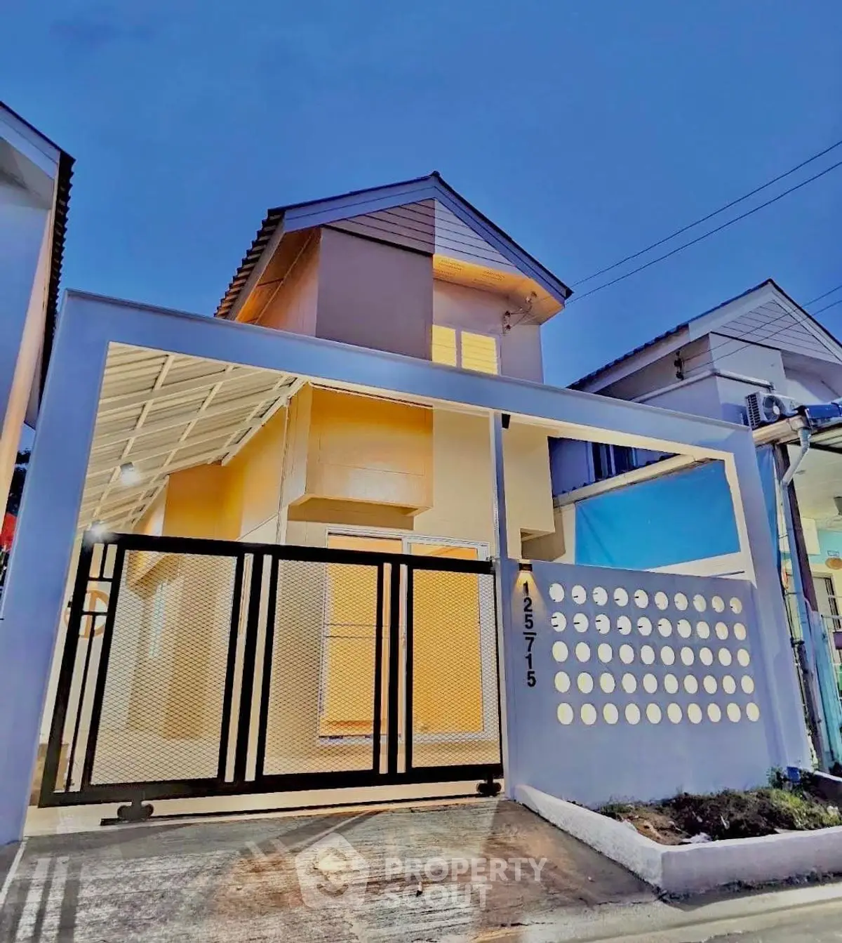 Modern two-story house with unique facade and gated entrance at dusk.