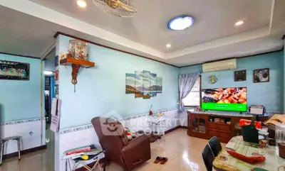 Cozy living room with modern decor, featuring a comfortable armchair, wall art, and a flat-screen TV.