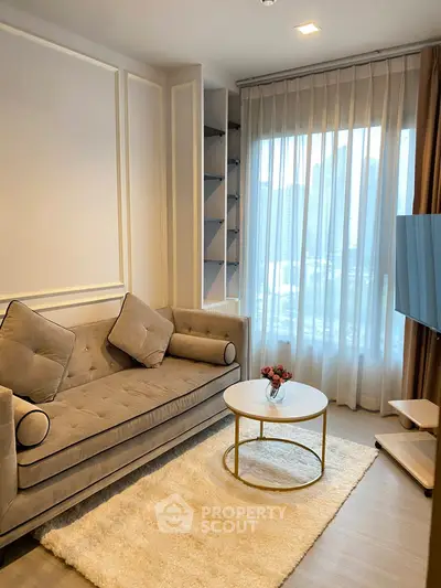 Elegant living room with plush sofa, round coffee table, and city view through sheer curtains.