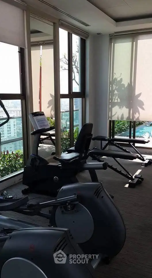 Luxurious gym with modern equipment and stunning city view, perfect for fitness enthusiasts.