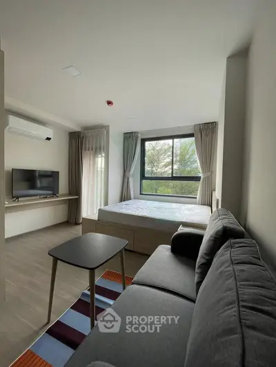 Modern studio apartment with large window and stylish furnishings