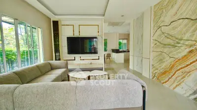 Luxurious living room with modern decor and large windows offering garden views.