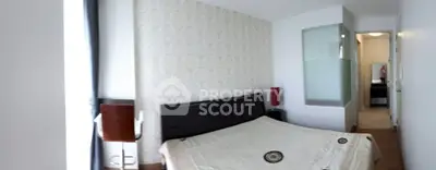 Cozy bedroom with modern decor and adjacent bathroom, featuring stylish wallpaper and natural light.