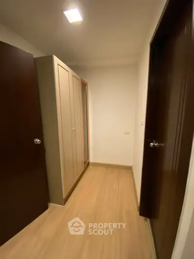 Compact storage area with wooden flooring and built-in wardrobe