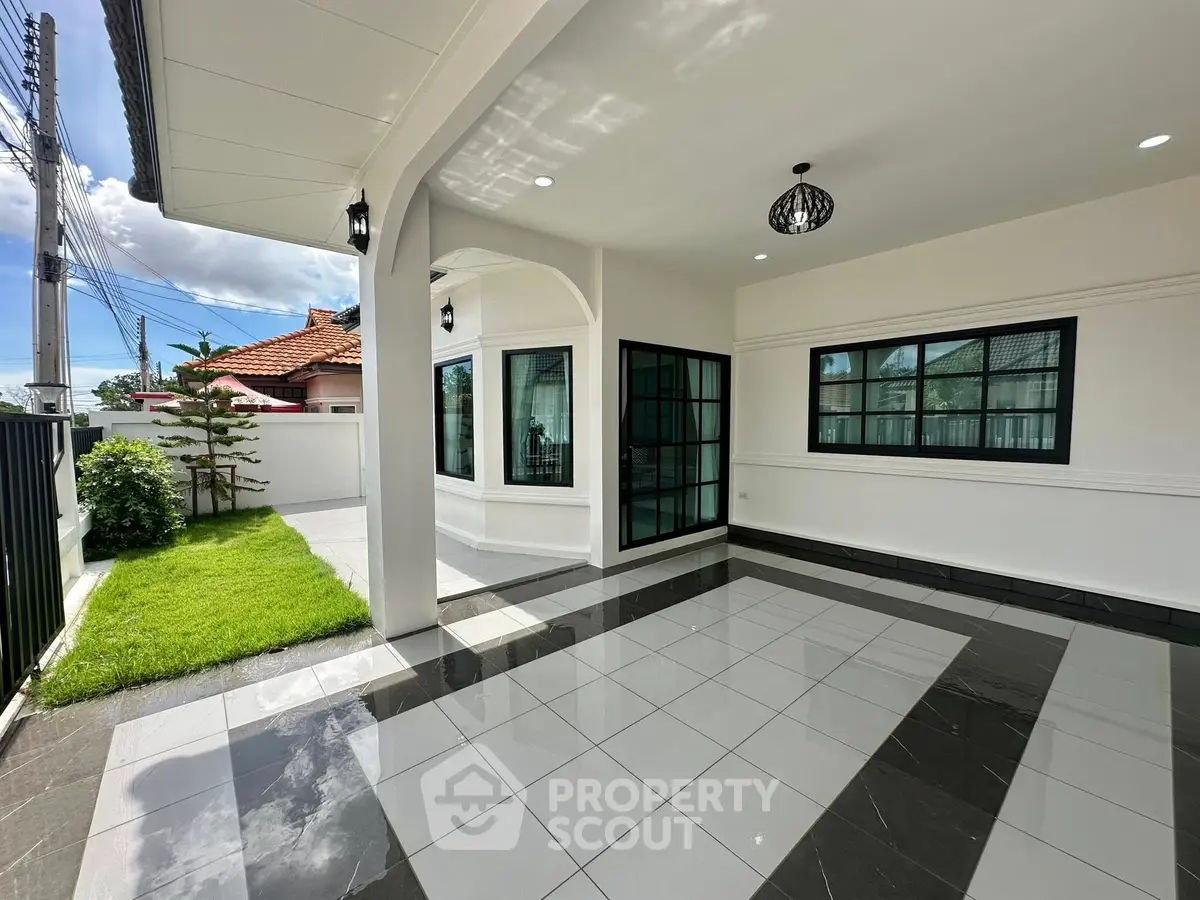 Modern home exterior with spacious tiled patio and lush green lawn