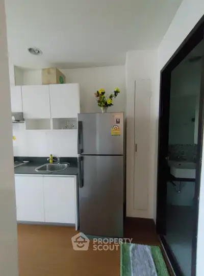Modern kitchen with sleek fridge and stylish cabinetry in a cozy apartment setting.