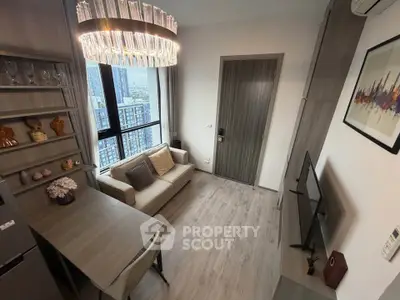 Modern living room with elegant chandelier and city view, featuring cozy sofa and wall-mounted TV.
