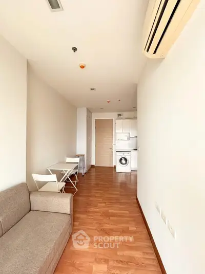 Modern apartment interior with wooden flooring, compact kitchen, and cozy living area.