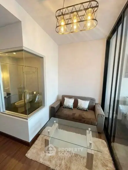 Cozy living room with modern glass coffee table and plush sofa, featuring stylish lighting and a unique glass partition.