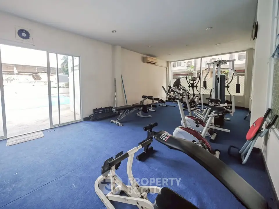 Spacious gym with modern equipment and pool view in luxury property