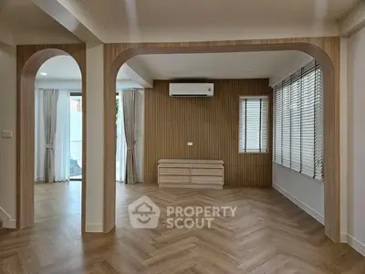 Spacious modern living room with elegant wooden flooring and stylish archways.
