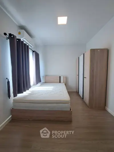 Modern minimalist bedroom with wooden flooring and ample natural light