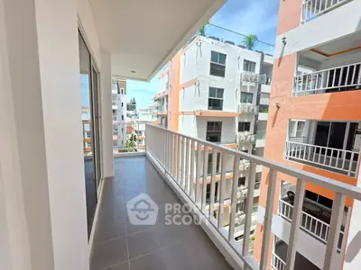 Spacious balcony with modern railing and city view in vibrant apartment complex