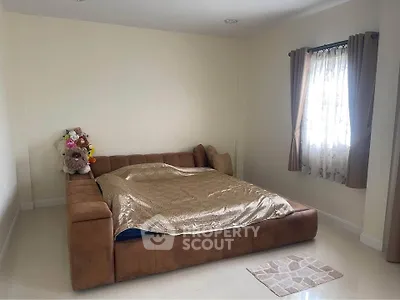 Spacious bedroom with cozy brown sofa bed and natural light from window.