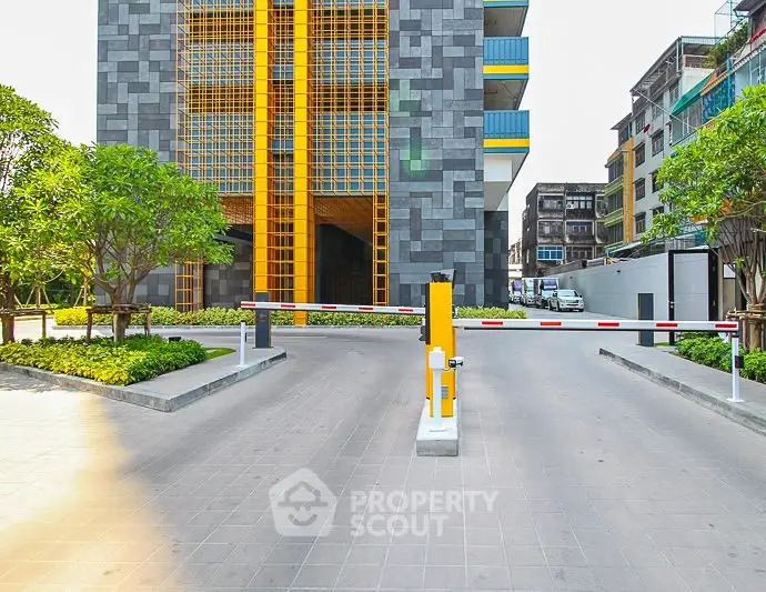 Modern building entrance with security barrier and vibrant yellow accents.