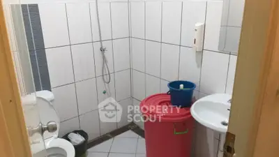 Compact bathroom with shower and toilet in tiled interior.