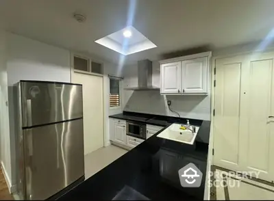 Modern kitchen with stainless steel appliances, ample cabinetry, and sleek black countertops, perfect for culinary enthusiasts.