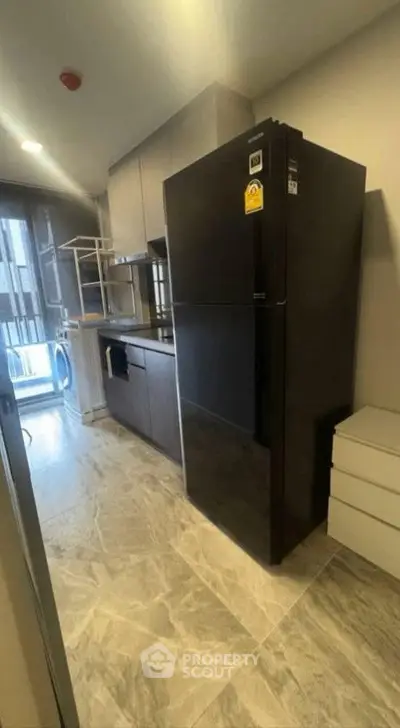 Modern kitchen with sleek black fridge and marble flooring in a stylish apartment.
