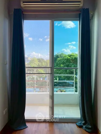 Bright balcony view with lush greenery and clear blue sky from a modern apartment.