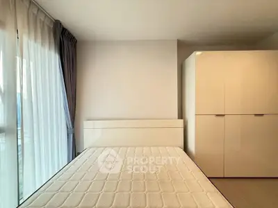 Modern bedroom with large window and sleek wardrobe, perfect for urban living.