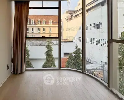 Spacious room with large windows offering urban views and natural light.