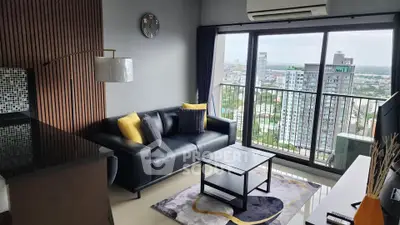 Modern living room with city view, stylish decor, and balcony access in high-rise apartment.