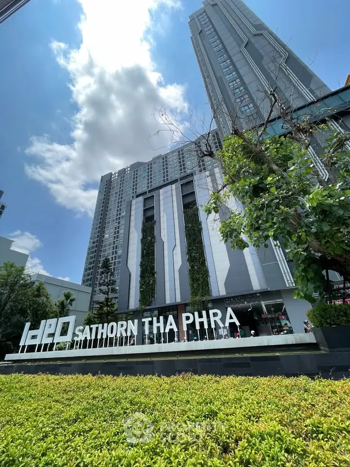 Modern high-rise building with lush greenery at IDEO Sathorn Tha Phra, showcasing urban living.