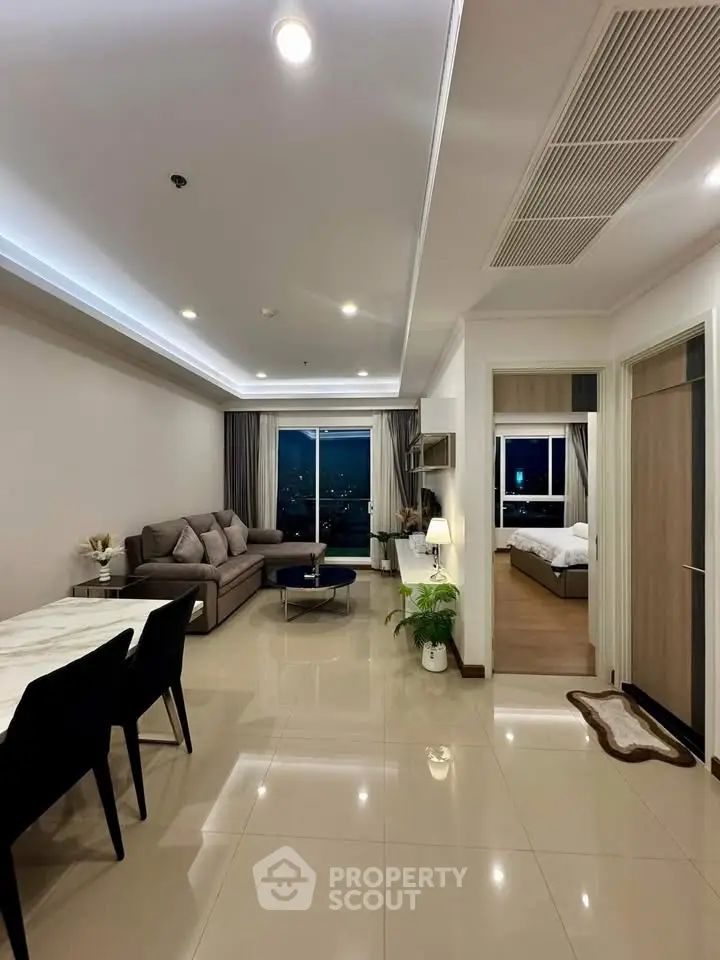 Modern open-plan living room with dining area and city view, featuring sleek furniture and elegant decor.