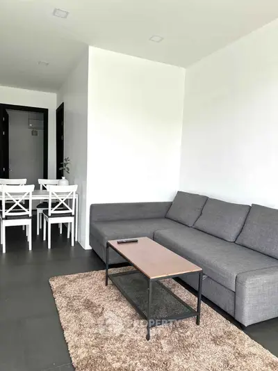 Modern living room with sleek gray sofa and stylish dining area in open layout.