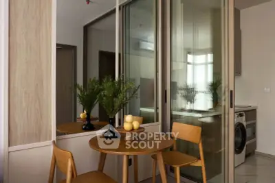 Modern dining area with wooden table and chairs, adjacent to a sleek kitchen with washing machine.