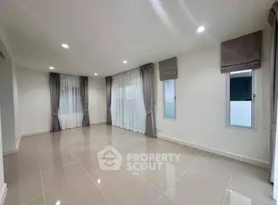 Spacious empty living room with large windows and elegant curtains