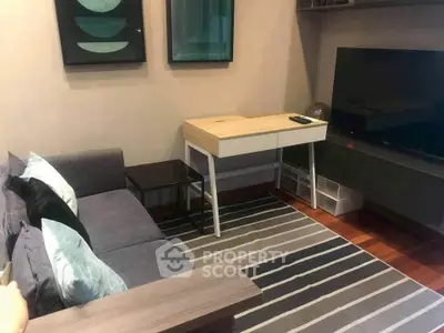 Cozy living room with modern decor, featuring a sleek sofa, stylish desk, and large flat-screen TV.