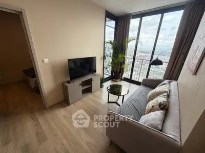 Modern living room with large windows and city view, featuring a cozy sofa and sleek TV stand.